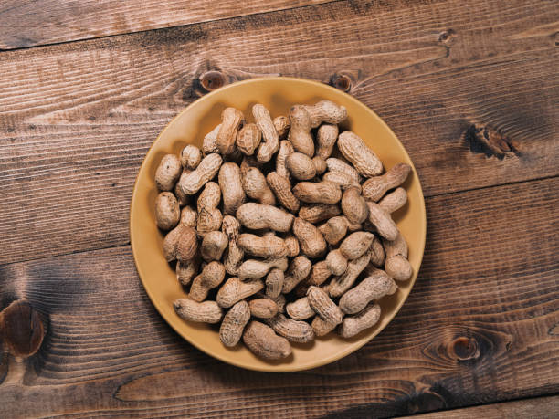 istock Freshly roasted peanuts on on a yellow ceramic plate on a wooden tabletop 1312265229