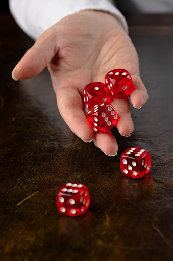 Woman's hand rolling dice onto an old leather lined table.