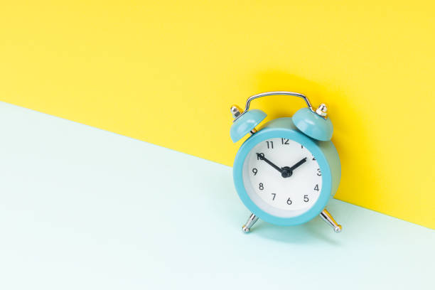istock blue alarm clock over yellow background. studio shot. time concept. template for design 1312266384