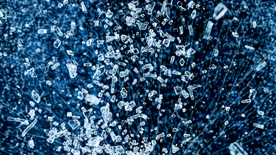 Close-up of falling glass shards against black background.