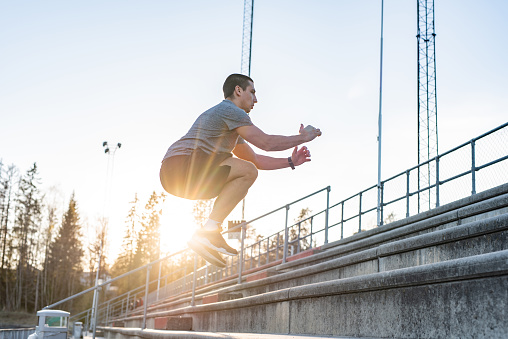 African American boy practicing long jump at athletics club at the stadium.