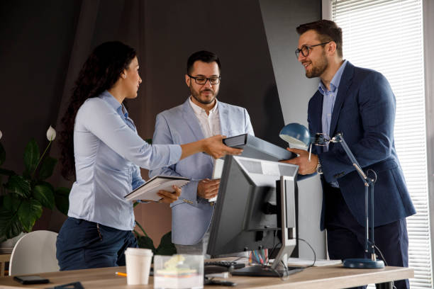 istock Coworkers exchanging file binders while talking business 1312269162