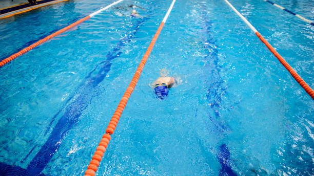 istock boy swims backstroke in a swimming pool for competition 1312270006