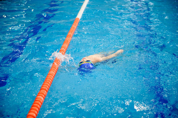 istock boy swims backstroke in a swimming pool for competition 1312270583