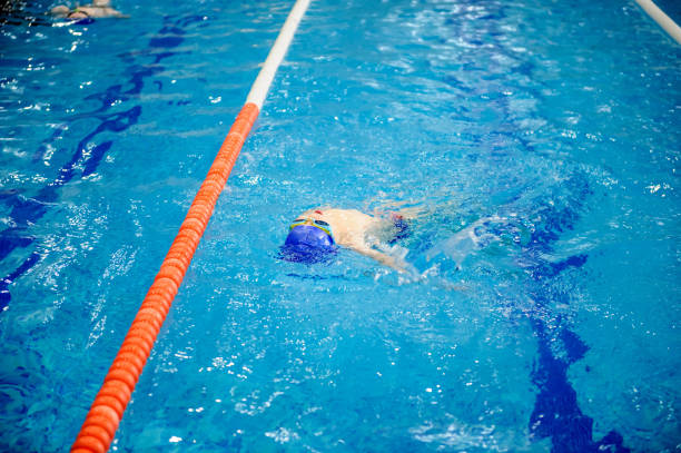 istock boy swims backstroke in a swimming pool for competition 1312270632
