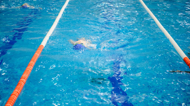istock boy swims backstroke in a swimming pool for competition 1312270679