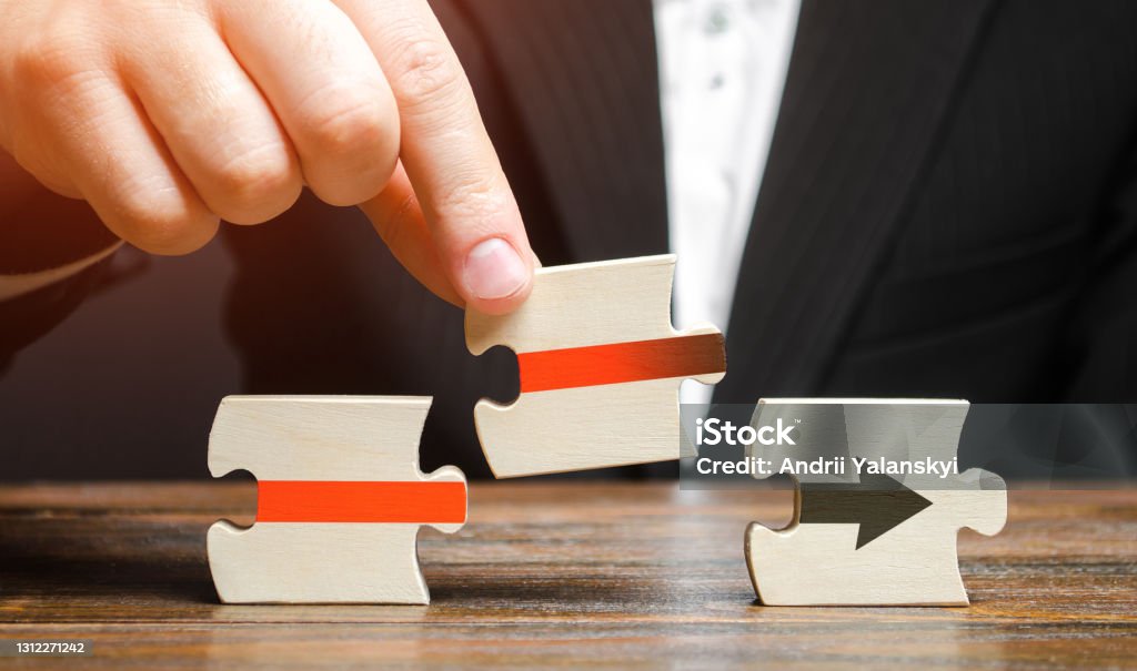 Businessman inserts the puzzle and completes the assembly of the red arrow. Business process formation. Roadmap agreement. Resuming and ensuring uninterrupted technological operation. Progress Continuity Stock Photo