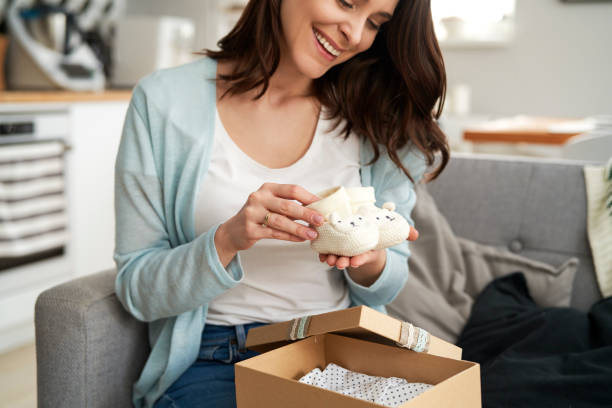 Happy woman holding knit baby booties Happy woman holding knit baby booties baby clothing stock pictures, royalty-free photos & images