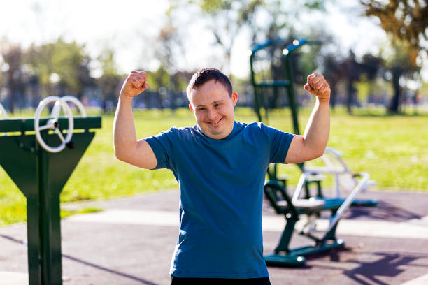 Young man with Down syndrome working out at outdoor gym in public park stock photo