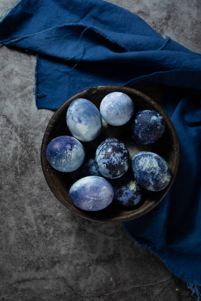 istock eggs are painted with blueberries in the form of a marble pattern. blue Easter eggs lie in a clay bowl on a stone background. 1312276437