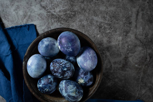 istock eggs are painted with blueberries in the form of a marble pattern. blue Easter eggs lie in a clay bowl on a stone background. 1312276481