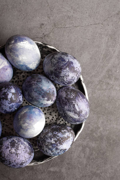 istock organic Easter eggs close-up, hand-painted with natural blueberries, lie in a clay cup on a stone table. Easter concept. flat lay 1312278124
