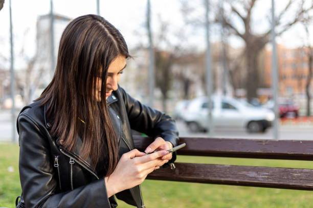 istock Girl is texting on the cellphone while sitting on the bench. 1312278558