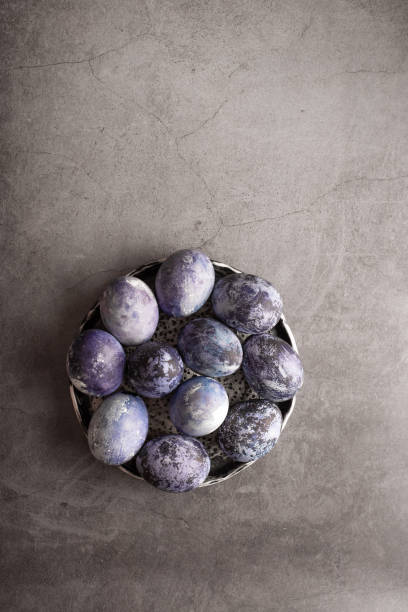 istock marble Easter eggs on a dark background, hand-painted with natural blueberries, lie in a clay cup on a stone table. Easter preparation concept. 1312280018