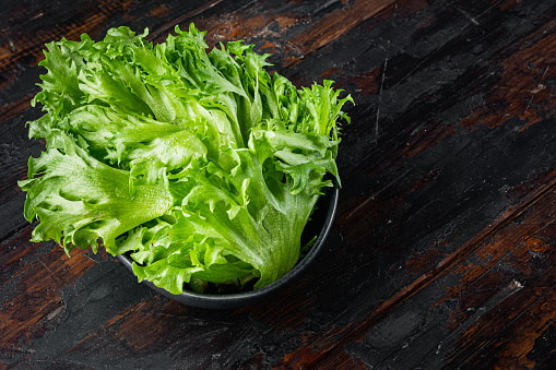 Fresh organic green batavia lettuce leaves, on old dark  wooden table background  with copy space for text