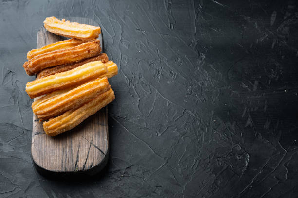 istock Traditional Spanish dessert churros with sugar and chocolate, on black background with space for text, copyspace 1312284750