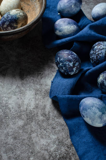 istock Easter eggs lie on a blue towel on a concrete background. coloring eggs for Easter with natural blueberry juice dye. 1312285069