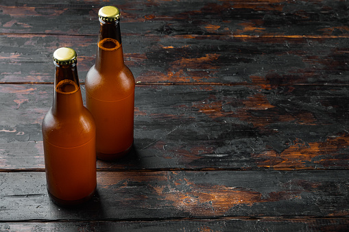 Glass bottles of beer set, on old dark  wooden table, with copy space for text