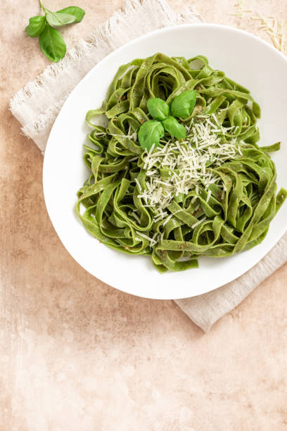 istock Spinach pasta with pesto sauce and grated cheese in a white plate 1312285529