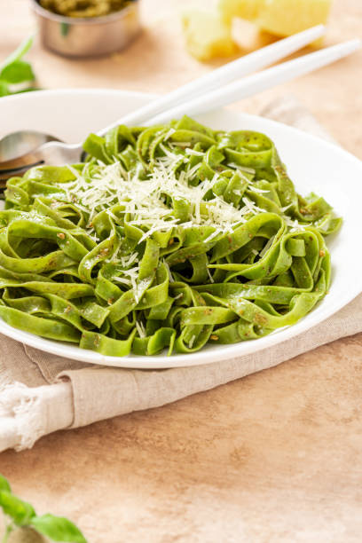 istock Spinach pasta with pesto sauce and grated cheese in a white plate 1312285618