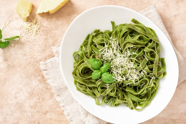 istock Spinach pasta with pesto sauce and grated cheese in a white plate 1312285636