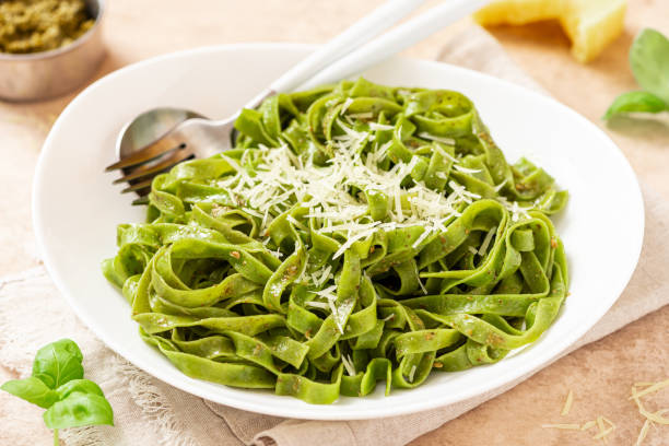 istock Spinach pasta with pesto sauce and grated cheese in a white plate 1312285722