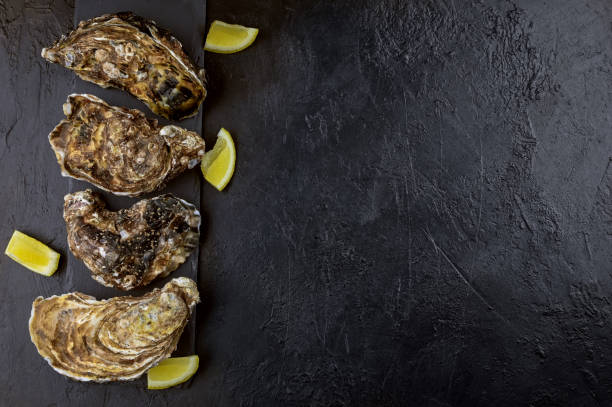 istock Flatlay with Oysters and lemons on a black slate background 1312287229