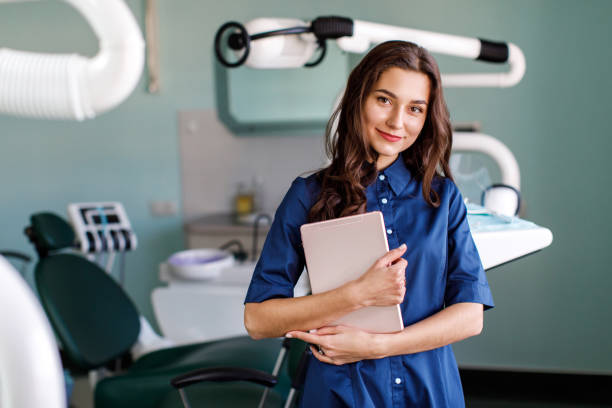 joven médico en una clínica dental. retrato de la joven doctora dentista con tableta digital en el consultorio dental - human mouth human teeth indoors young women fotografías e imágenes de stock