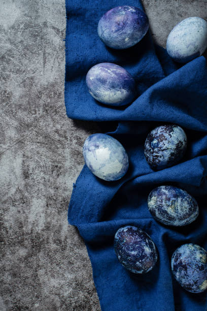 istock Easter eggs lie on a blue towel on a concrete background. coloring eggs for Easter with natural blueberry juice dye. 1312288210