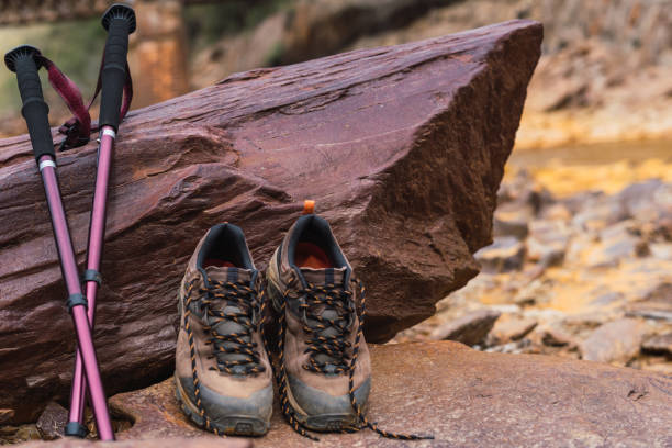 primo piano di scarponi da trekking e bastoncini da trekking su una roccia rossa a fuoco. rocce del rio tinto. - at the bottom of boot sole of shoe shoe foto e immagini stock