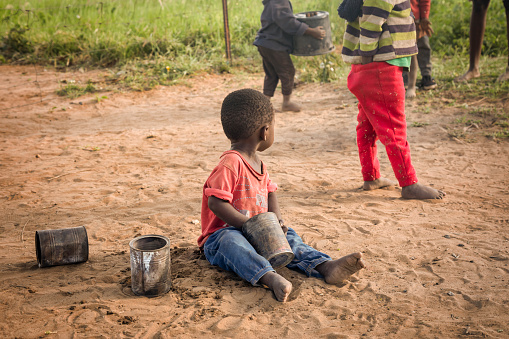 African children playing with tin cans in the sand in a village in Botswana