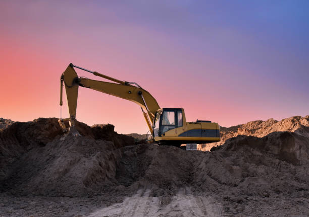 Excavator working on earthmoving at open pit mining on sunset background Excavator working on earthmoving at open pit mining on sunset background. Backhoe digs sand and gravel in quarry. Heavy construction equipment during excavation at construction site Earthmoving stock pictures, royalty-free photos & images