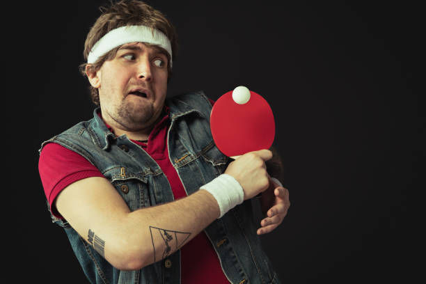 istock Young Caucasian funny man playing ping pong isolated on black background. 1312300094