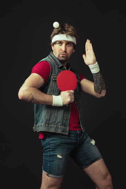 istock Young Caucasian funny man playing ping pong isolated on black background. 1312300097