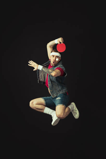 jeune homme drôle caucasien jouant le ping-pong d’isolement sur le fond noir. - facial expression unpleasant smell shirt caucasian photos et images de collection