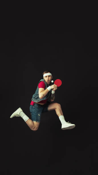 jeune homme drôle caucasien jouant le ping-pong d’isolement sur le fond noir. - facial expression unpleasant smell shirt caucasian photos et images de collection