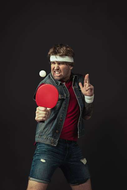 istock Young Caucasian funny man playing ping pong isolated on black background. 1312300110