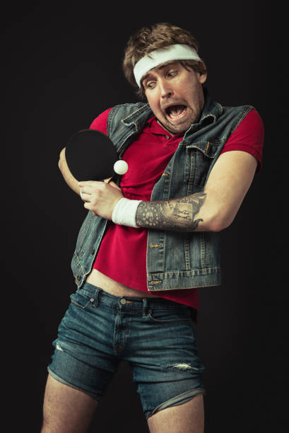 istock Young Caucasian funny man playing ping pong isolated on black background. 1312300126