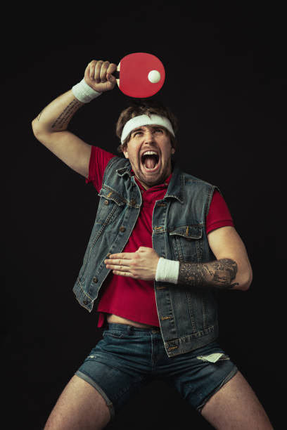 jeune homme drôle caucasien jouant le ping-pong d’isolement sur le fond noir. - facial expression unpleasant smell shirt caucasian photos et images de collection