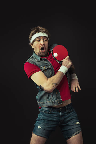 istock Young Caucasian funny man playing ping pong isolated on black background. 1312300135