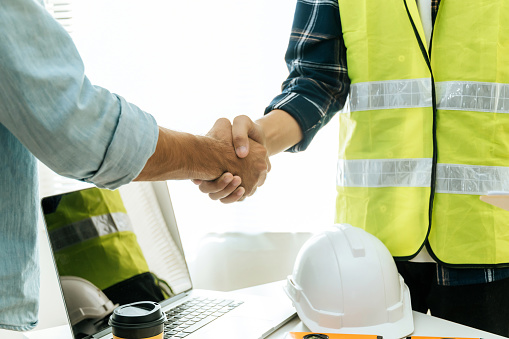engineer, architect, construction worker team hands shaking after plan project contract on workplace desk in meeting room office at construction site, contractor, partnership, construction concept
