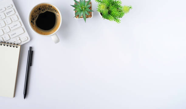 istock Top view above of White office desk table with keyboard, notebook and notepad, coffee cup with equipment office supplies. Business and finance concept. Workplace, Flat lay with blank copy space. 1312301560