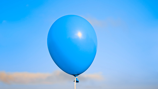 Close-up of blue balloon flying against sky.