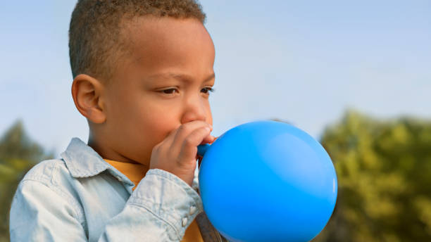 istock Boy blowing balloon outdoors 1312302368