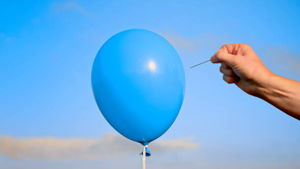 istock Man popping blue balloon with pin 1312302376