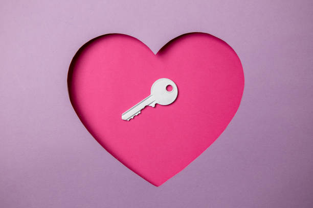 a chave branca está localizada em uma cavidade rosa em forma de coração. ao redor é roxo. - lock padlock steel closing - fotografias e filmes do acervo
