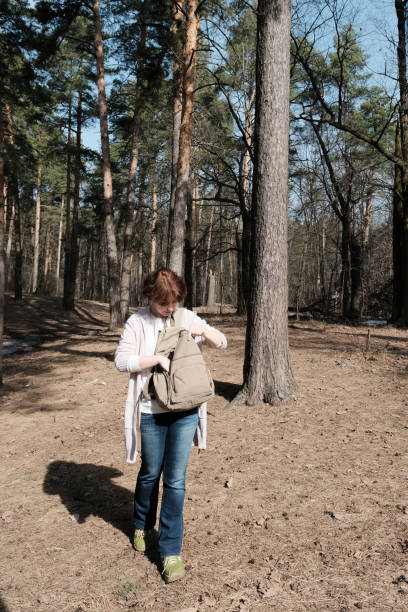 istock Mature woman is looking for something in her backpack while walking in sunny forest 1312302748