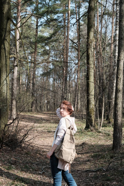 istock Mature woman is standing and looking around while walking in sunny forest 1312302803
