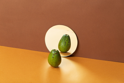 Fresh avocados in mirror reflection. Copy space