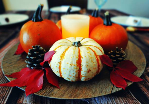 Thanksgiving centerpiece of pumpkins, leaves, candle and pine cones
